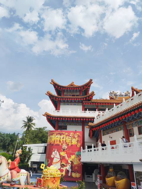       Brightly colored Thean Hou Temple roofs adorned with red lanterns against white clouds in Kuala Lumpur.
  