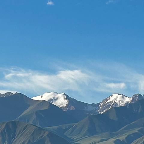       Distant snow-capped mountain peaks under a clear blue sky.
  