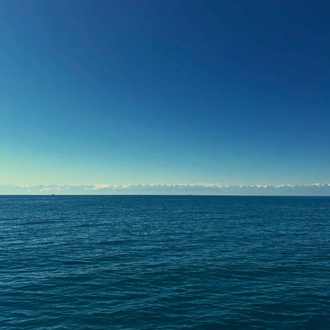       Vast blue lake stretching to the horizon with distant snow-covered mountain range.
  