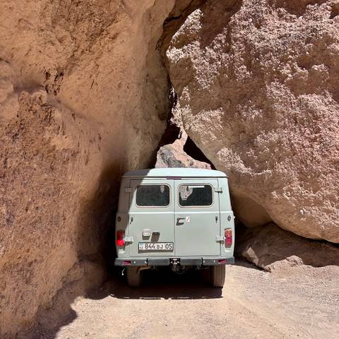       Vintage light-blue van wedged between towering rock walls on a narrow track
  