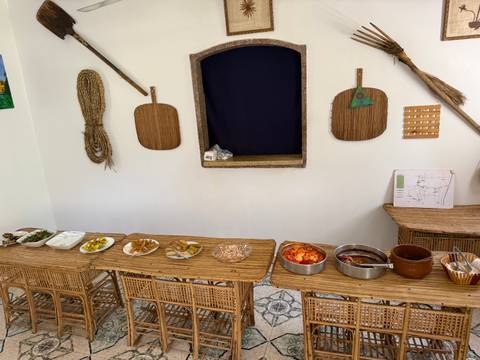       Simple buffet layout with assorted Egyptian dishes on wicker tables against a white wall.
  