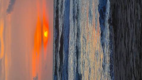       Vibrant orange sun setting over rolling ocean waves and a sandy shore.
  