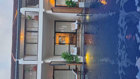       Modern resort room opening onto a pool with subtle evening lighting.
  