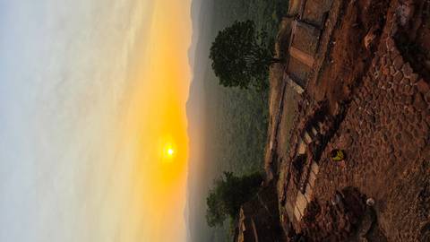       Golden sunrise illuminating forested plains viewed from an ancient stone terrace high above.
  