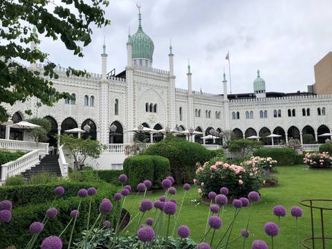       Moorish-style white façade of the Nimb Hotel with arches, domes and lush flower garden in front.
  