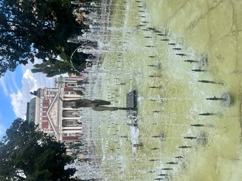       Dancing fountain spraying water jets in front of Sofia's ornate National Theatre on a bright afternoon.
  