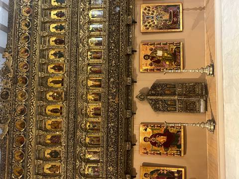       Richly decorated iconostasis with gilded religious paintings and ornate wood carvings displayed in a museum hall.
  