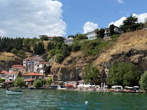       Cliff-side village and rocky beach along the clear waters of Lake Ohrid in summer.
  