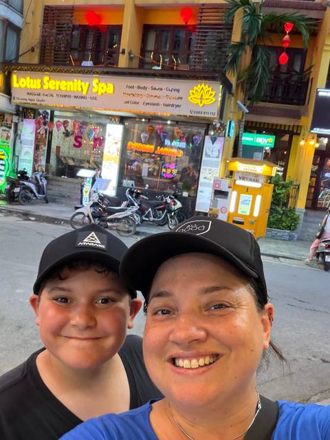       Nighttime selfie of mother and son under neon lights on a busy Vietnamese street
  