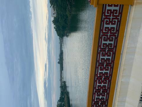       Vertical view of a tranquil river under pastel dawn sky framed by decorative bridge railing
  