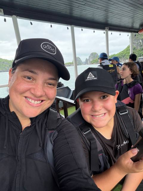       Boat selfie of mother and son wearing backpacks while cruising Ha Long Bay
  