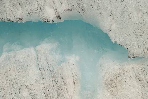       Close view of vibrant blue glacial ice crevasse within a rugged ice wall.
  