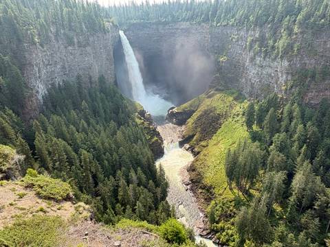       Tall waterfall plunging into a forested canyon with mist rising (same perspective as earlier).
  