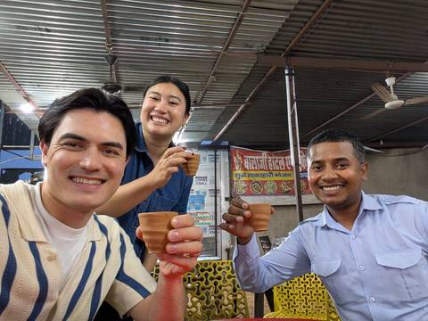       Three friends clinking clay chai cups inside a rustic Indian tea stall.
  