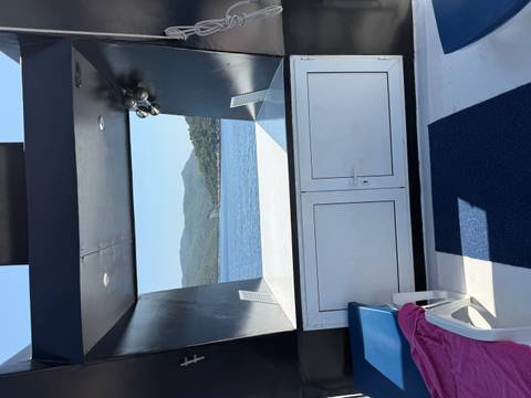      Open deck area of a yacht looking out to calm blue sea and forested islands.
  