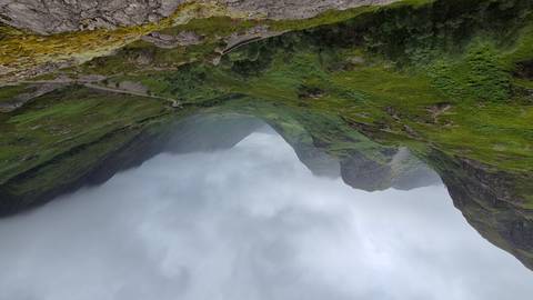       Dramatic green valley of Glencoe with winding road under brooding low clouds.
  