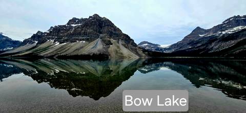       Mirror-calm Bow Lake reflecting surrounding peaks, with text label overlaid.
  