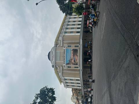       Trang Tien Plaza, an elegant cream-colored colonial style department store, anchors a busy Hanoi intersection.
  