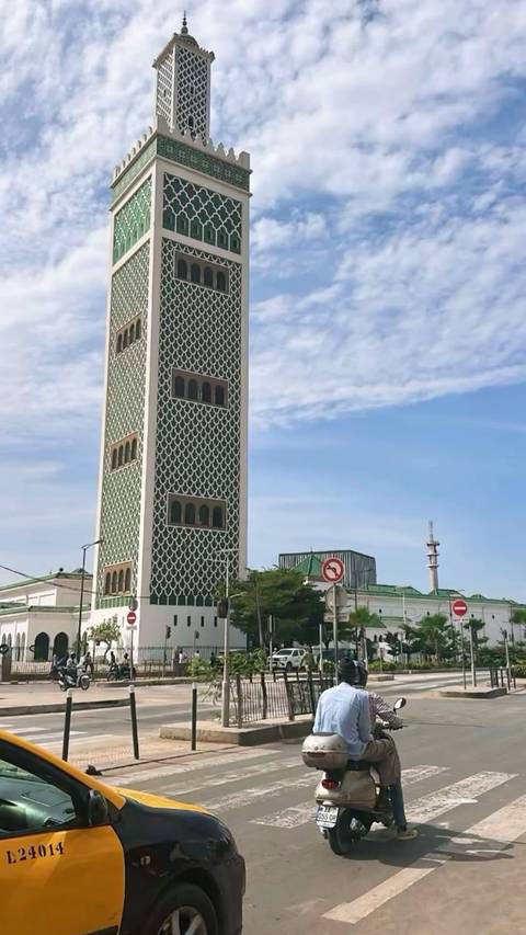       Tall green-tiled mosque minaret rising against a bright blue sky
  