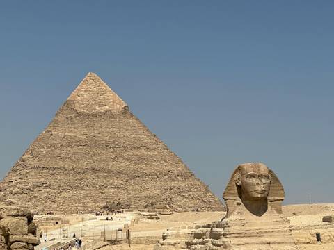       Classic view of the Great Pyramid of Giza with the Sphinx in the foreground against a clear blue sky.
  