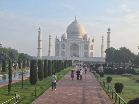       Iconic Taj Mahal mausoleum with reflecting pools and formal gardens in soft morning light.
  