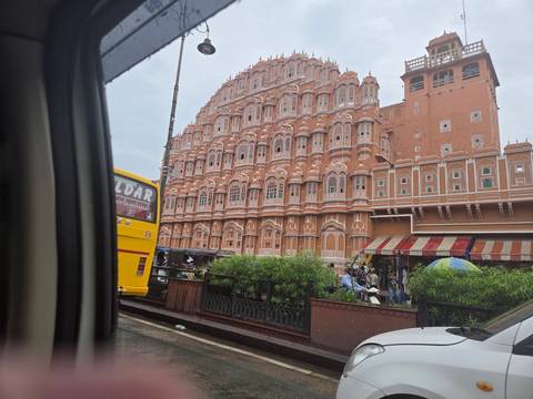       Side view of iconic pink Hawa Mahal palace captured from passing vehicle.
  