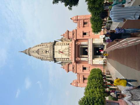       Visitors posing in front of a tall pink Hindu temple with stepped entrance path
  