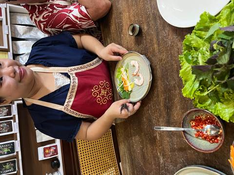       Cooking class participant in apron assembling fresh spring rolls on a plate.
  