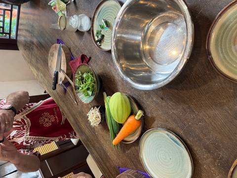       Wooden table set with fresh carrot, zucchini, sprouts and herbs during a culinary workshop.
  