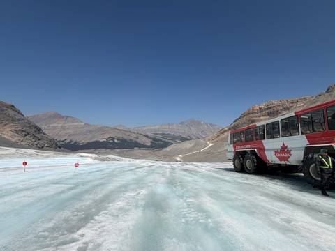       Ice Explorer bus parked on Columbia Icefield glacier with Rocky Mountains backdrop.
  