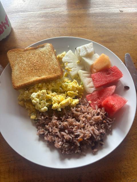       Breakfast plate with scrambled eggs, toast, rice and fresh tropical fruit slices.
  