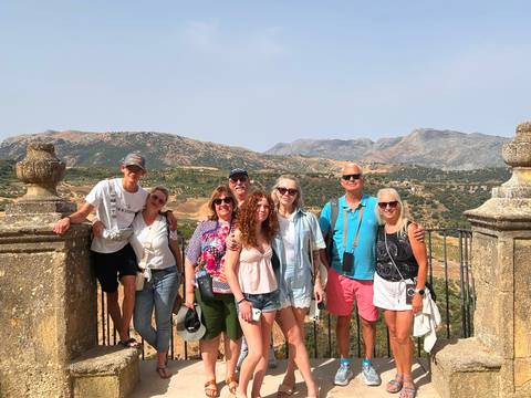       Family group posing at a stone viewpoint with rolling Andalusian hills behind
  