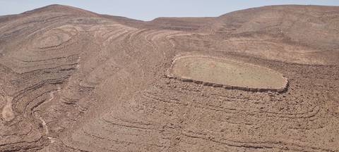       Close-up of swirling rock layers forming circular patterns in an arid landscape.
  