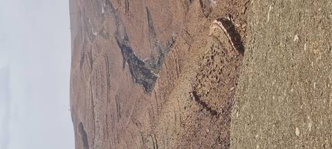       Layered, rocky desert hills with a deep eroded gully cutting through.
  