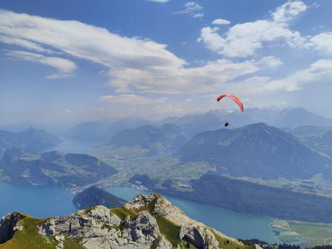       Paraglider soars high above deep blue lake and rugged alpine peaks.
  