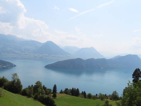       Serene alpine lake surrounded by hazy blue mountains under a bright sky.
  