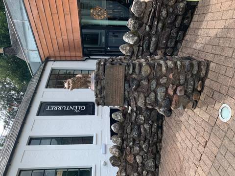       Bronze statue of Towser the distillery cat perched on a stone plinth outside The Glenturret visitor centre.
  