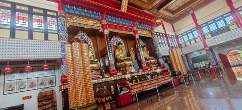       Ornate buddhist temple interior with golden statues and red columns
  