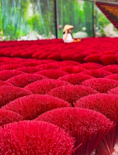       Close-up rows of bright red incense sticks bundled for drying create a vibrant pattern.
  