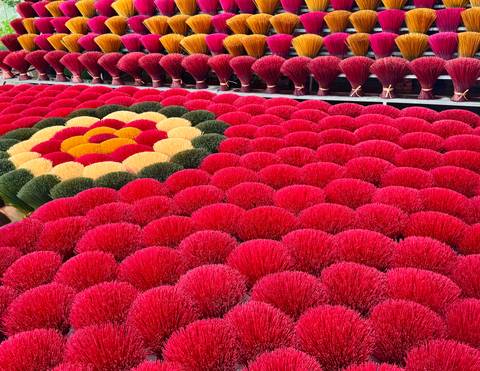       Incense bundles arranged in geometric flower pattern with dominant red color.
  