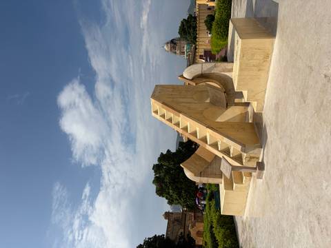       Stone masonry staircase sundial at Jantar Mantar observatory under partly cloudy sky.
  
