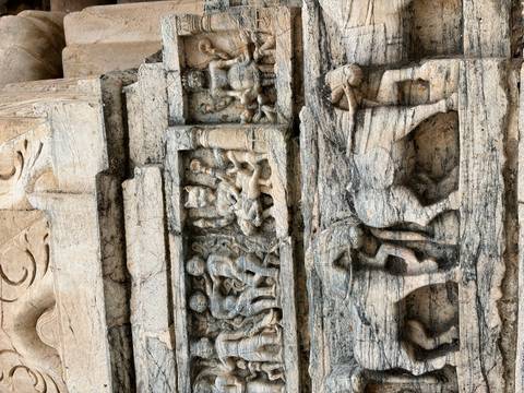       Close-up of intricate stone carvings featuring human figures and elephants on an ancient temple wall
  