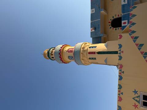      Colourful minaret of a Nubian village mosque standing against a clear blue sky.
  