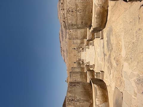       Stone courtyard lined with massive carved jars and statues amid ancient temple ruins.
  