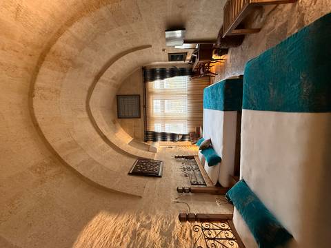       A cozy cave-style hotel room with stone vaulted ceilings and twin beds accented by teal linens.
  