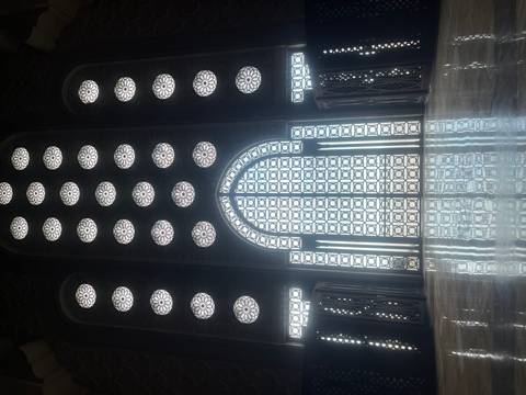       Majestic patterned glass window wall inside Hassan II Mosque casting reflective light on the polished floor.
  