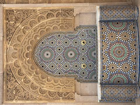       Colorful mosaic fountain set in an ornate carved stone archway.
  