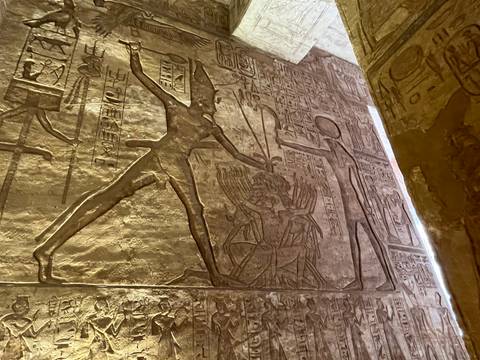       Detailed stone bas-relief of a pharaoh in combat carved into a temple wall.
  