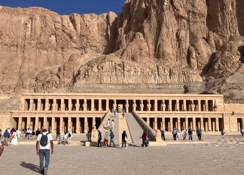       Grand façade of Hatshepsut’s Temple at Deir el-Bahri with tourists ascending the central ramp.
  