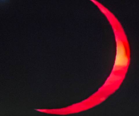       Blurry close-up of a red crescent shape against a black background.
  